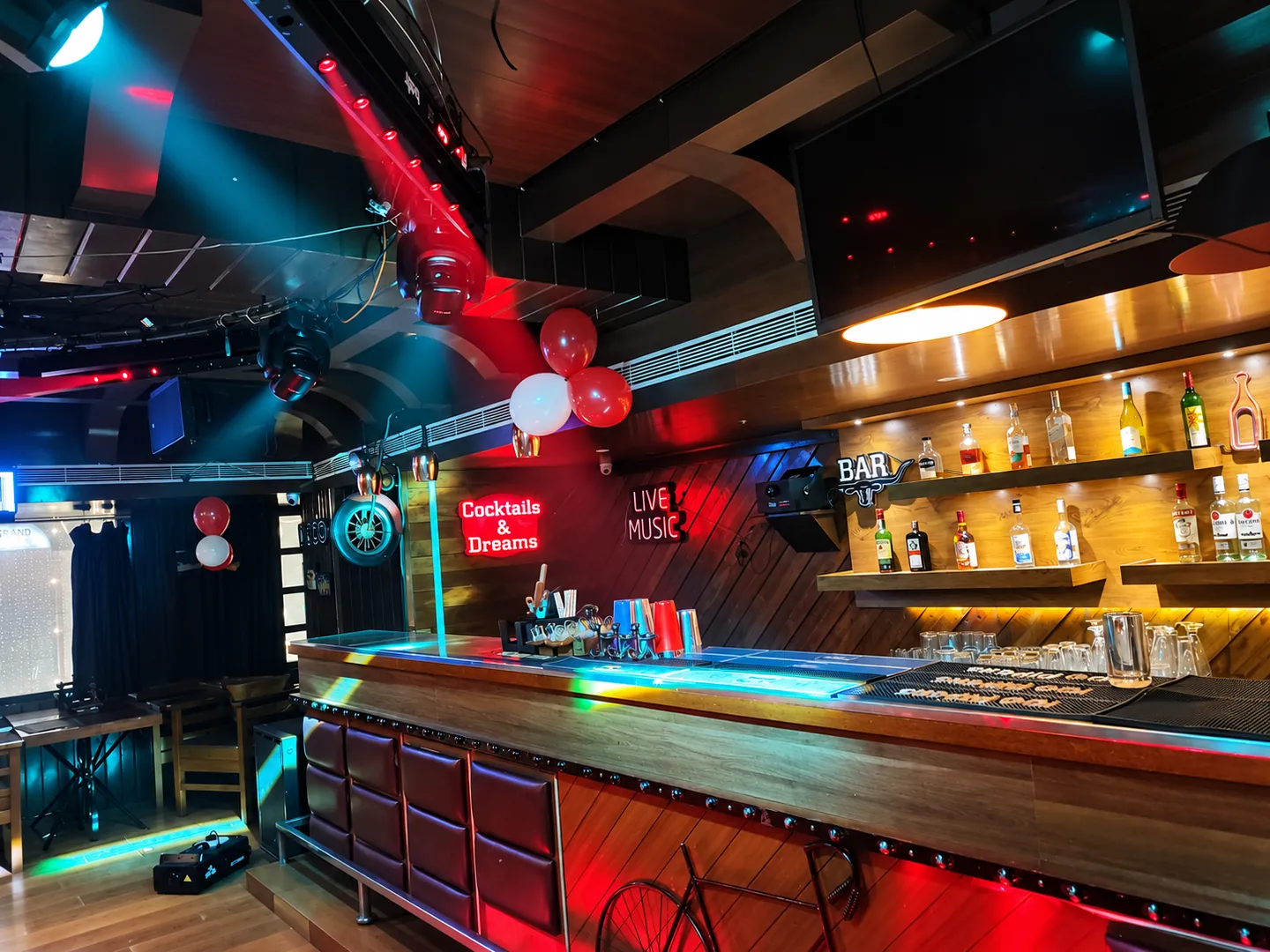 The BAR CODE bar counter, lit in low amber and red, with bottles on backlit wooden shelves.